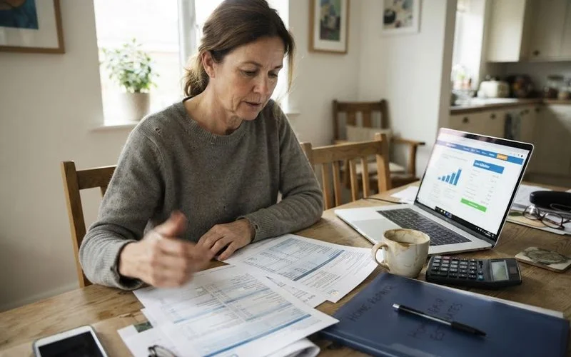 A homeowner reviews financing paperwork and a loan program brochure at a kitchen table